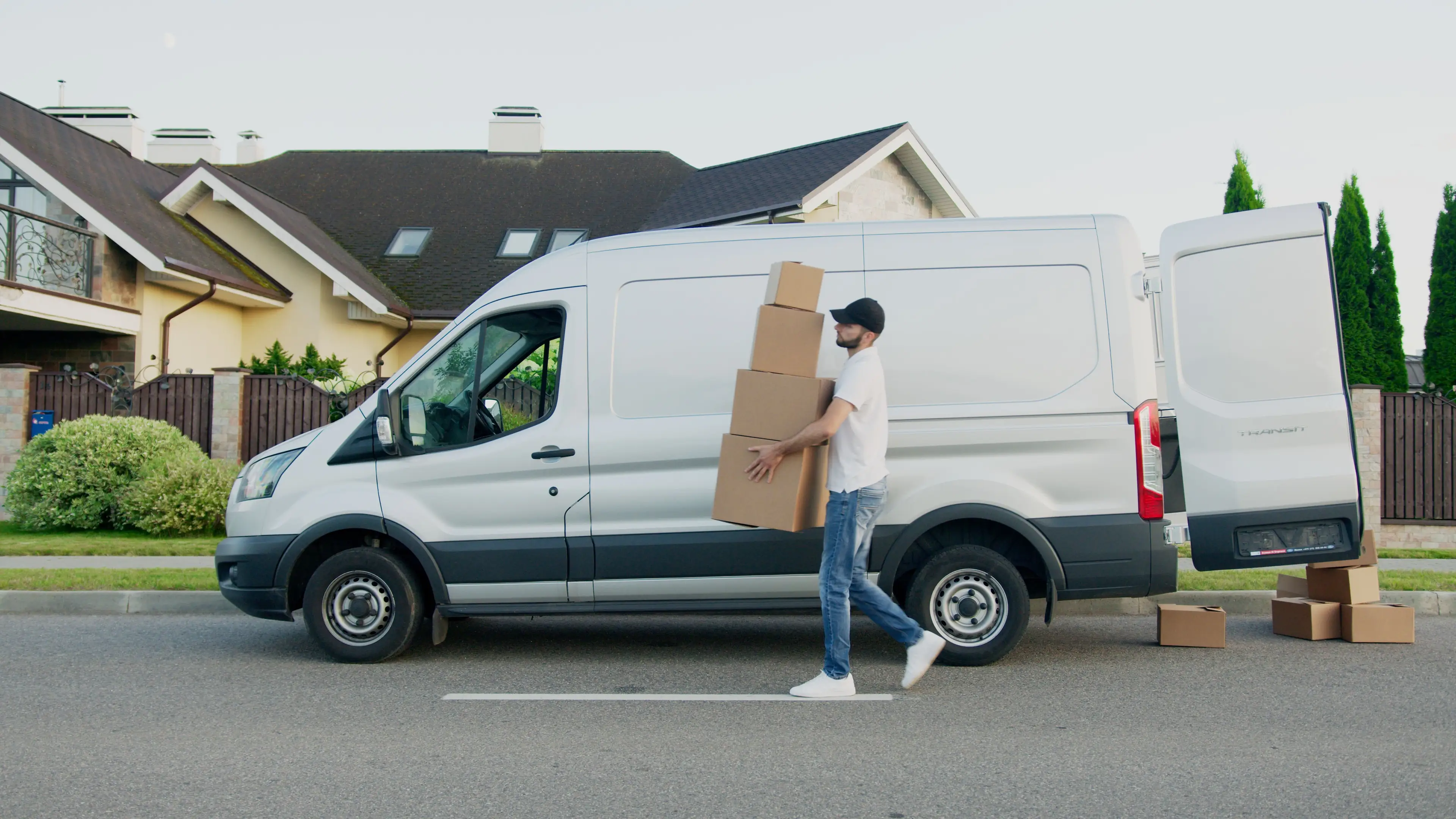Courier carrying parcels beside a delivery van