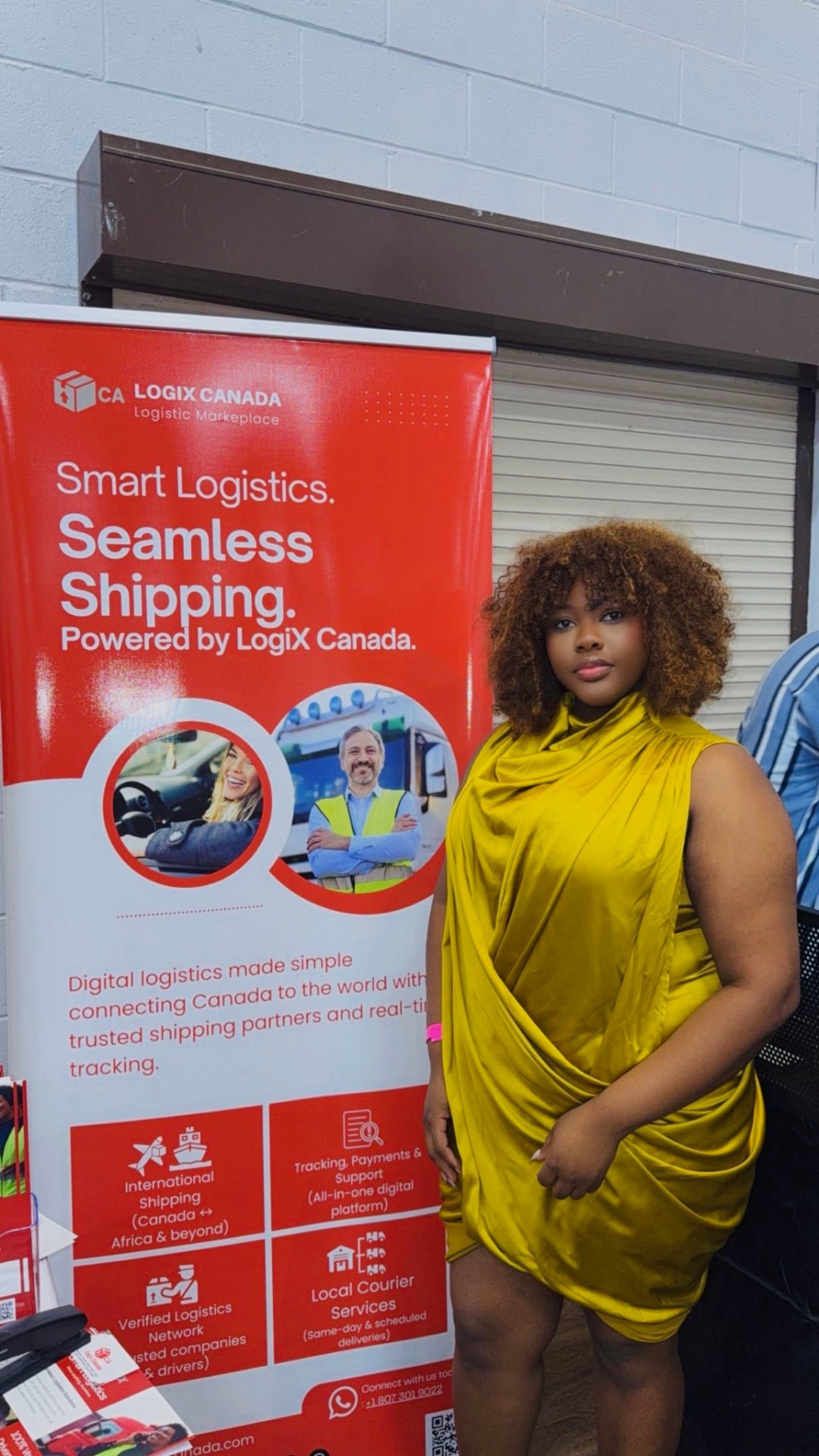 Guest in a yellow dress posing next to the LogiX Canada banner at Abula, Nkwobi & Grills in Edmonton